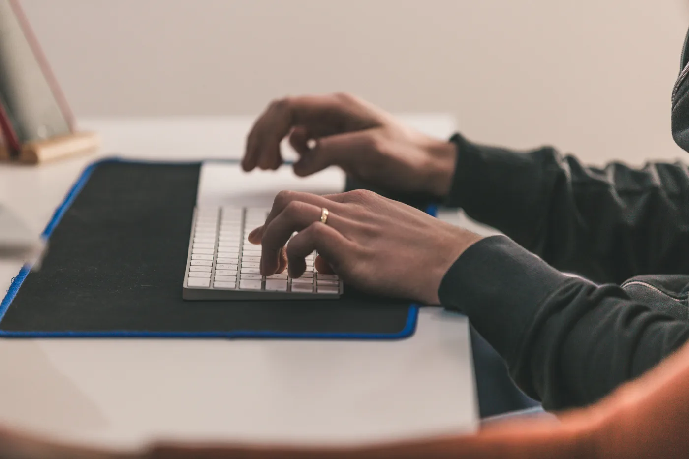 Close-up of a GearedApp team member typing on an Apple Magic Keyboard at a desk in the studio