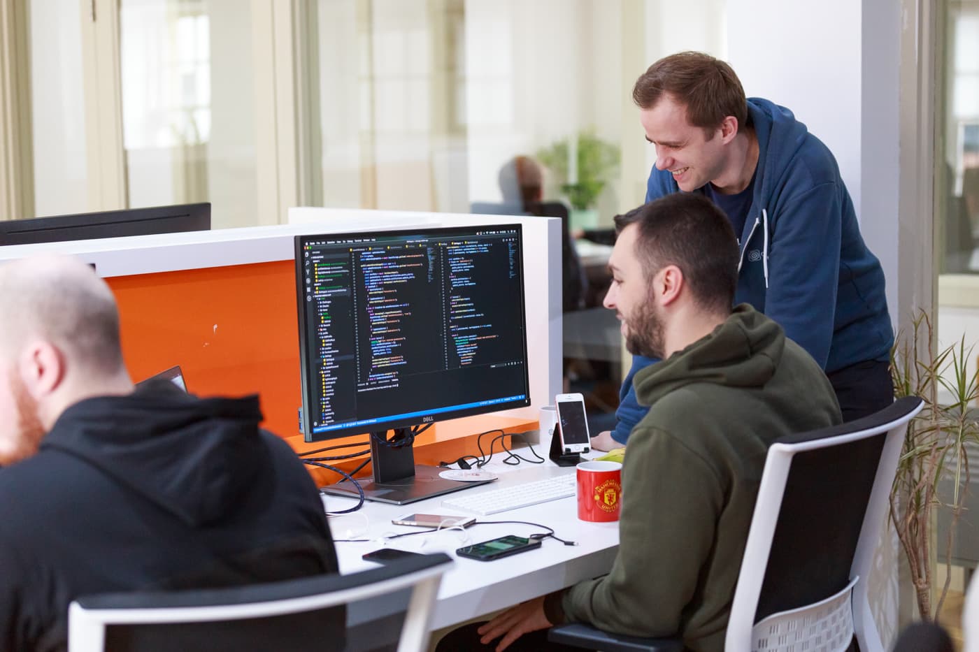 Two GearedApp engineers reviewing code together at a shared monitor in our Edinburgh studio