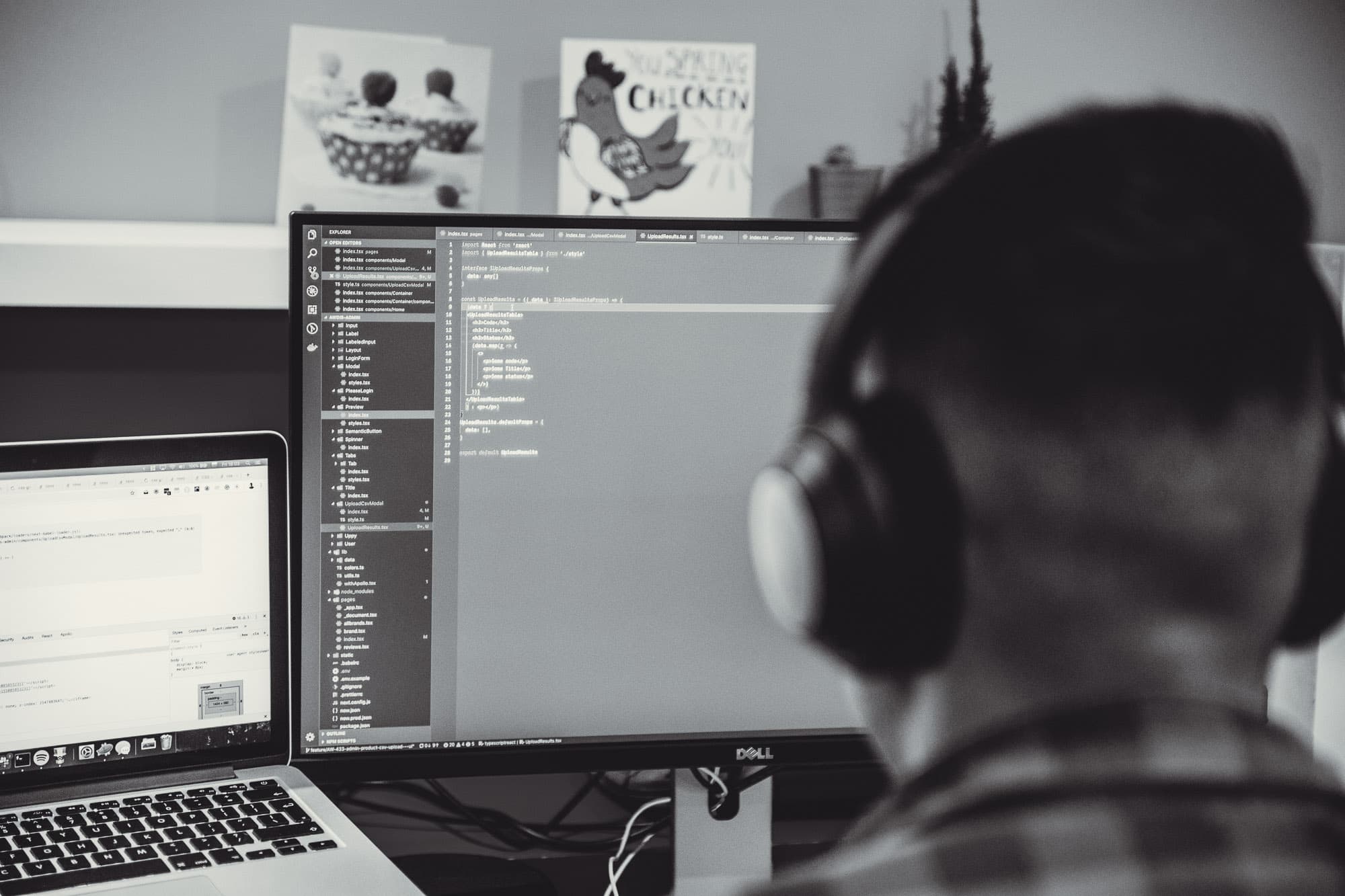 A software developer with headphones and glasses reviewing code across multiple monitors