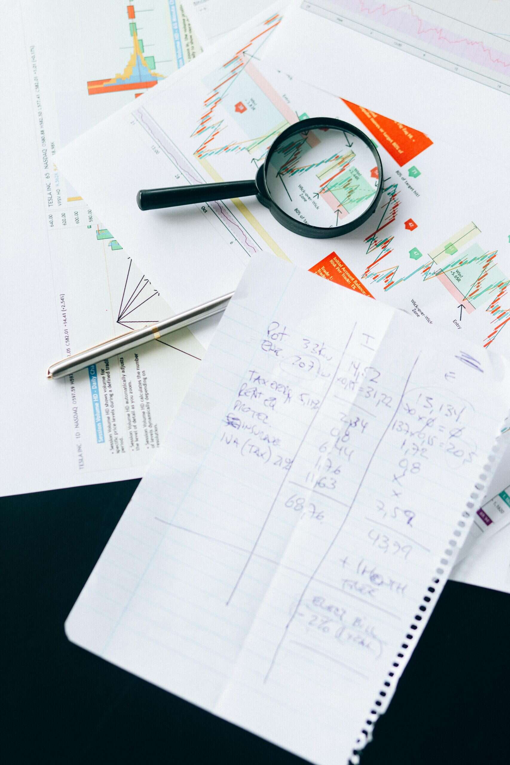 Business data displayed on paper print outs with magnifying glass