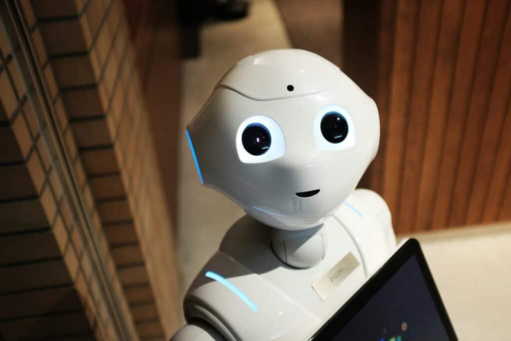 Image of a white robot with human features looking with big curious eyes