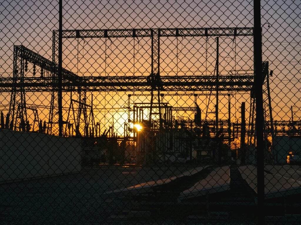Silhouette of industrial power lines during sunset, symbolising renewable energy